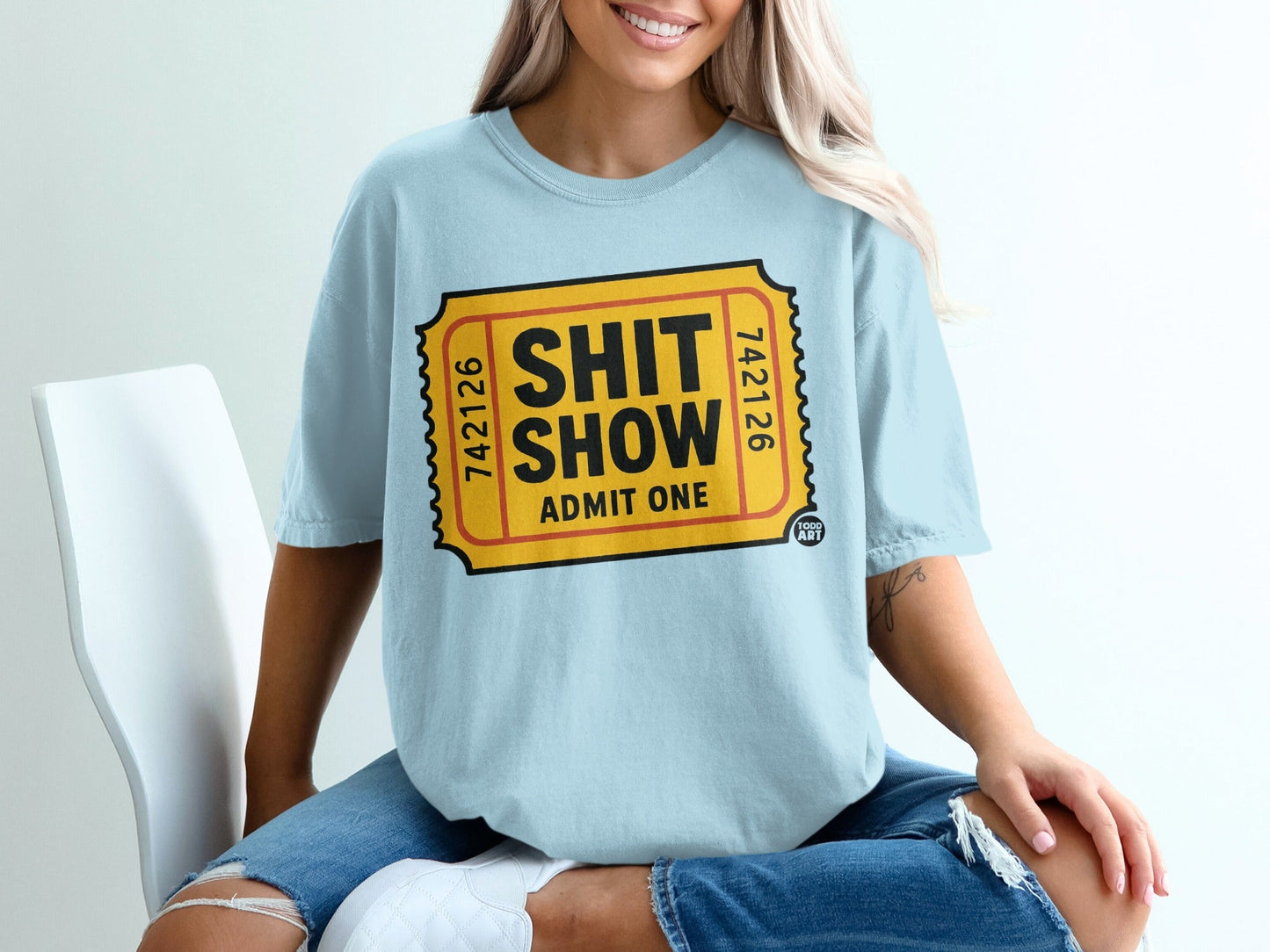Light blue t-shirt with a yellow ticket graphic that says "SHIT SHOW ADMIT ONE".