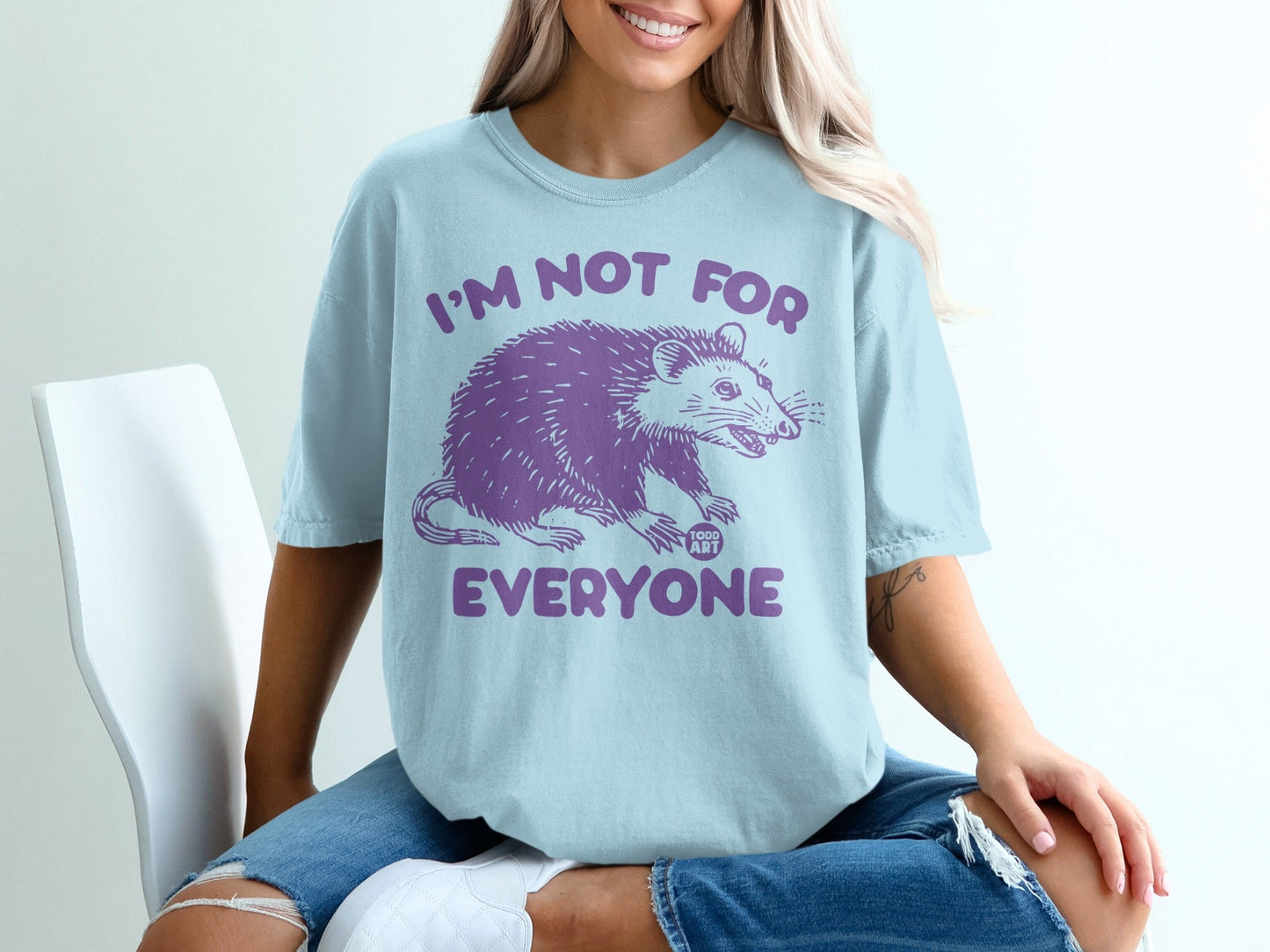 Light blue t-shirt with purple opossum graphic and "I'M NOT FOR EVERYONE" text.