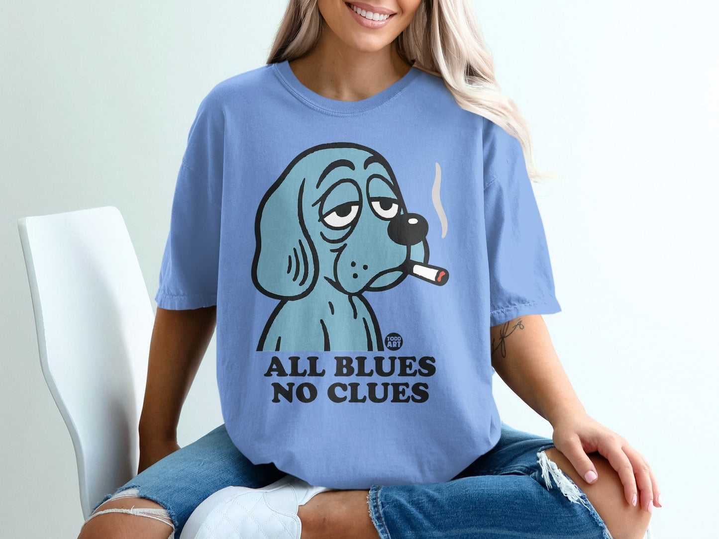 Blue cartoon dog wearing a t-shirt that says "ALL BLUES NO CLUES".