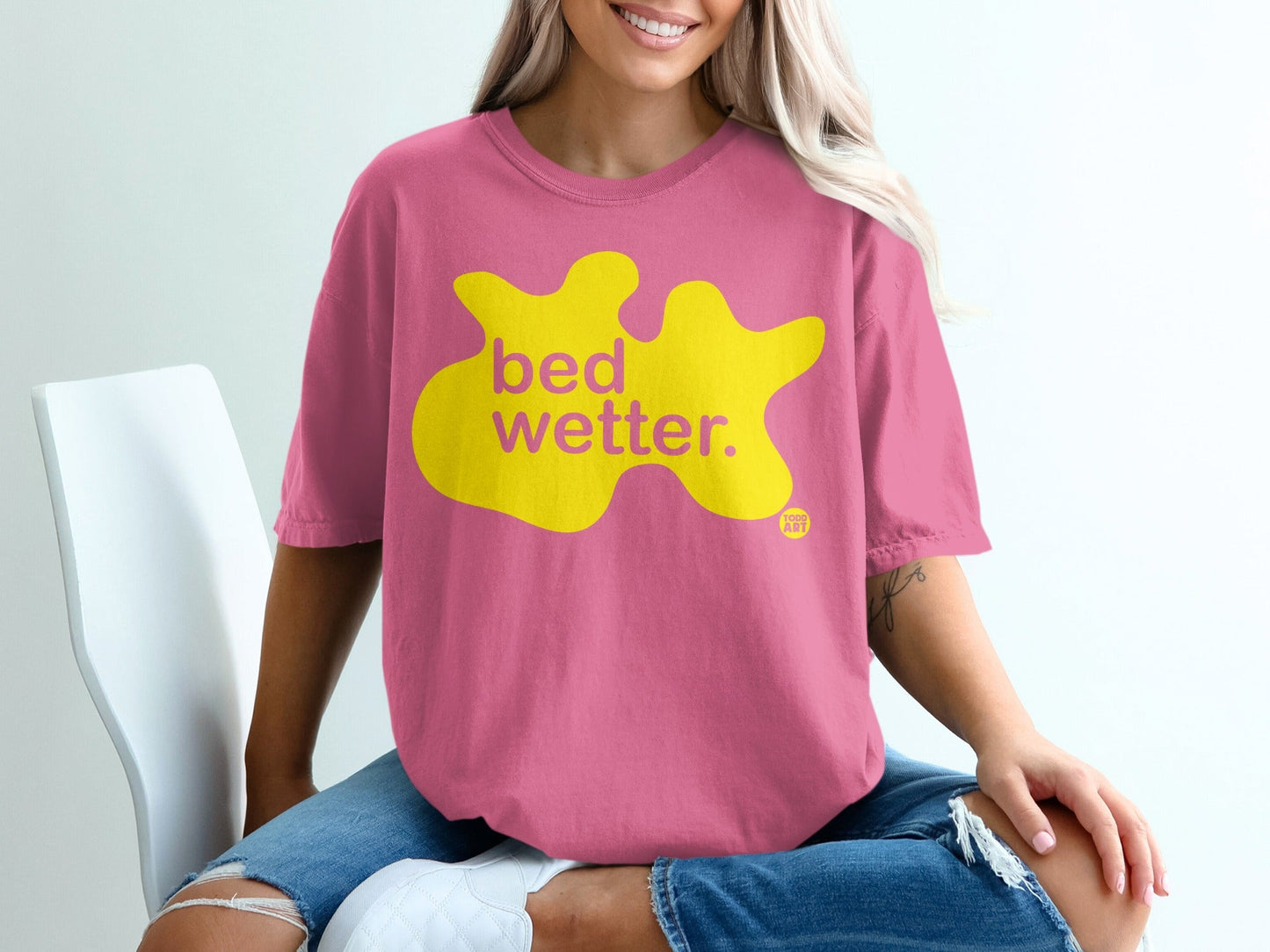 Pink t-shirt with yellow "bed wetter." text and a small logo.
