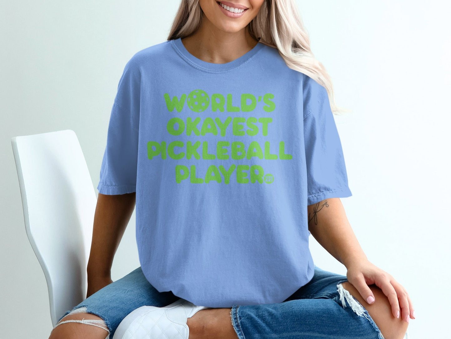 Blue t-shirt with "World's Okayest Pickleball Player" text and pickleball graphic.