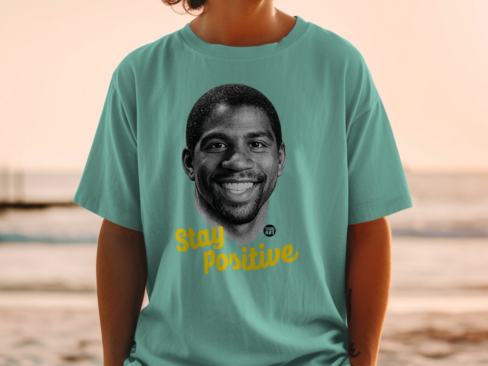 Teal t-shirt with Magic Johnson portrait and "Stay Positive" text.