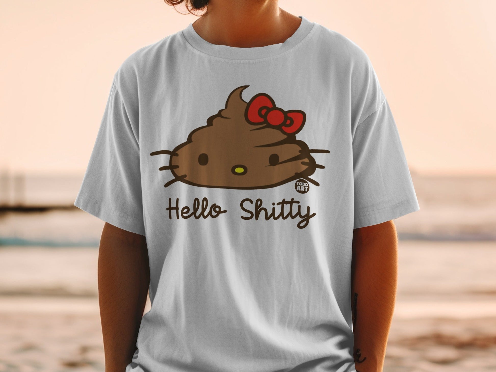 White t-shirt featuring a brown Hello Kitty character with a red bow, smiling.