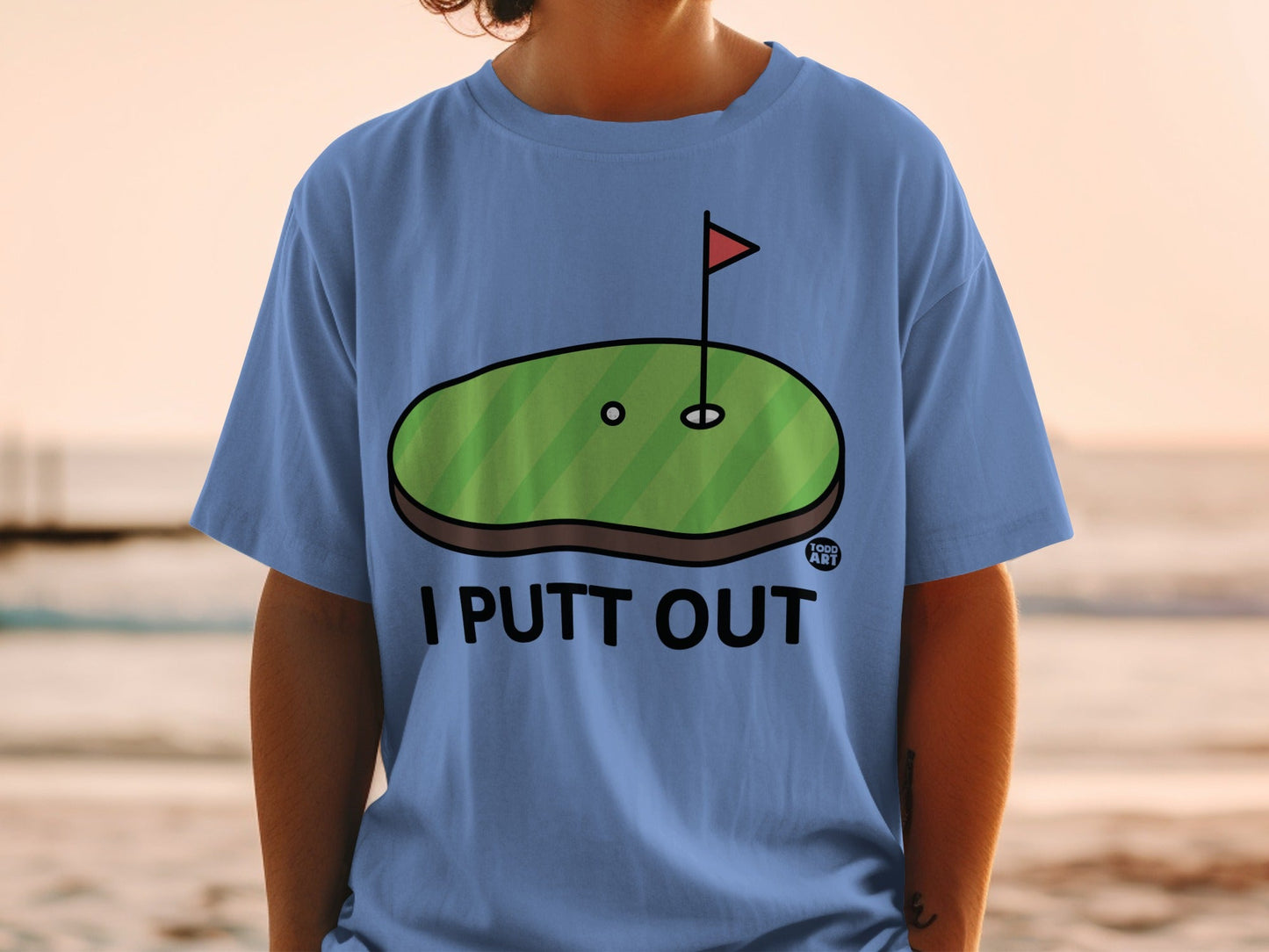 Blue t-shirt with cartoon golf green and "I PUTT OUT" text.