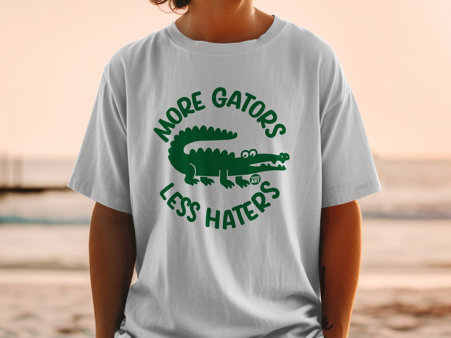 White t-shirt with green alligator graphic and "MORE GATORS LESS HATERS" text.