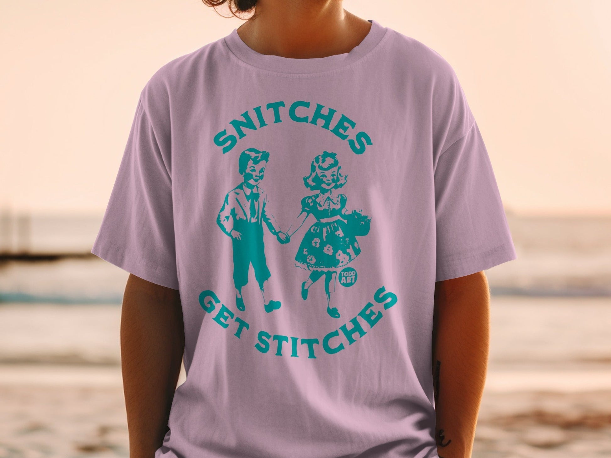 T-shirt with graphic of children, "Snitches Get Stitches," on a person.