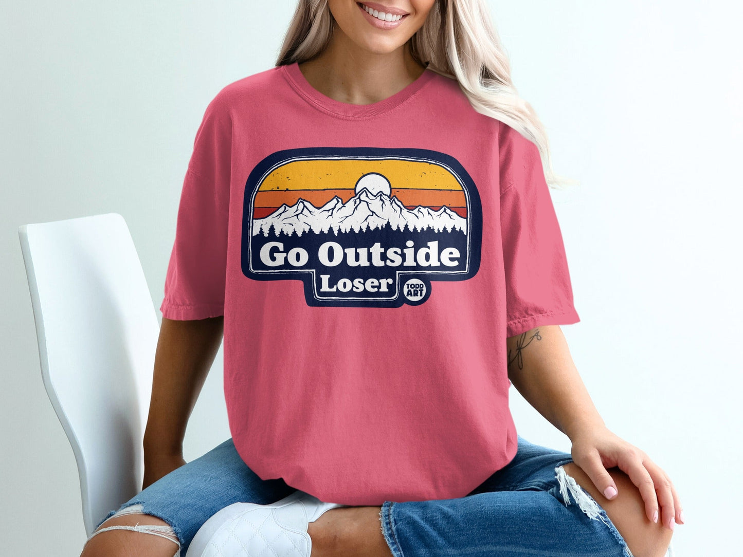Pink t-shirt with "Go Outside Loser" mountain and sun graphic.