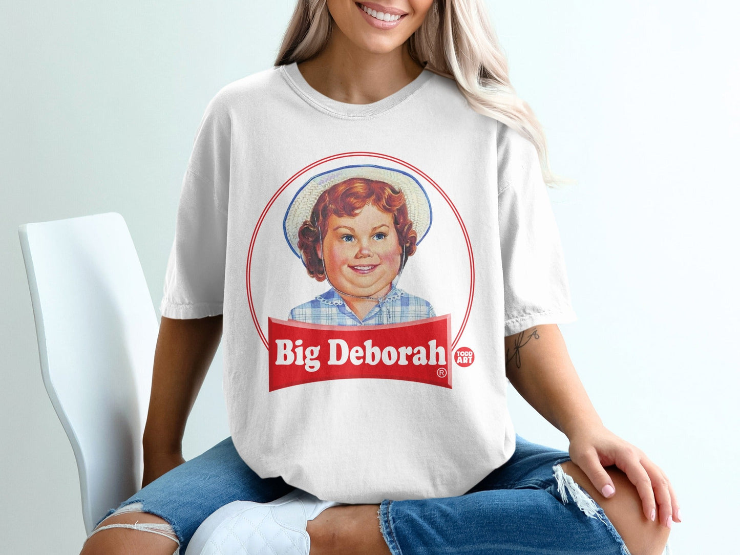 White t-shirt with Big Deborah Todd Art logo featuring a smiling child in a hat.