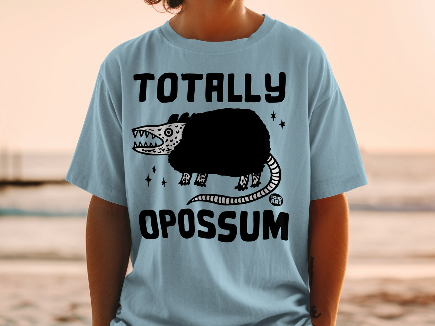 Light blue t-shirt with "TOTALLY OPOSSUM" graphic featuring a cartoon opossum.