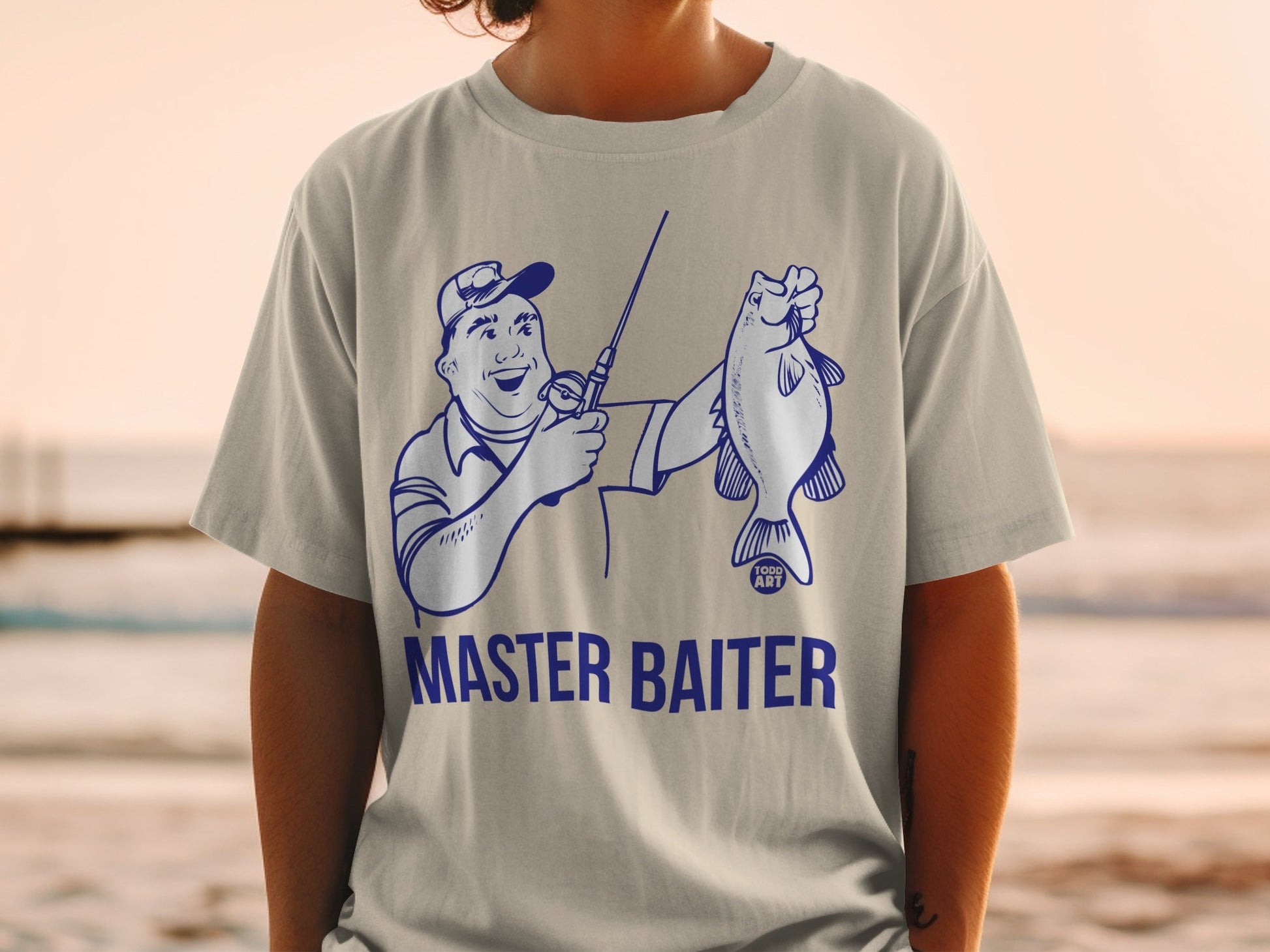 Man in t-shirt holding a fish, text "MASTER BAITER" and "TODD ART".