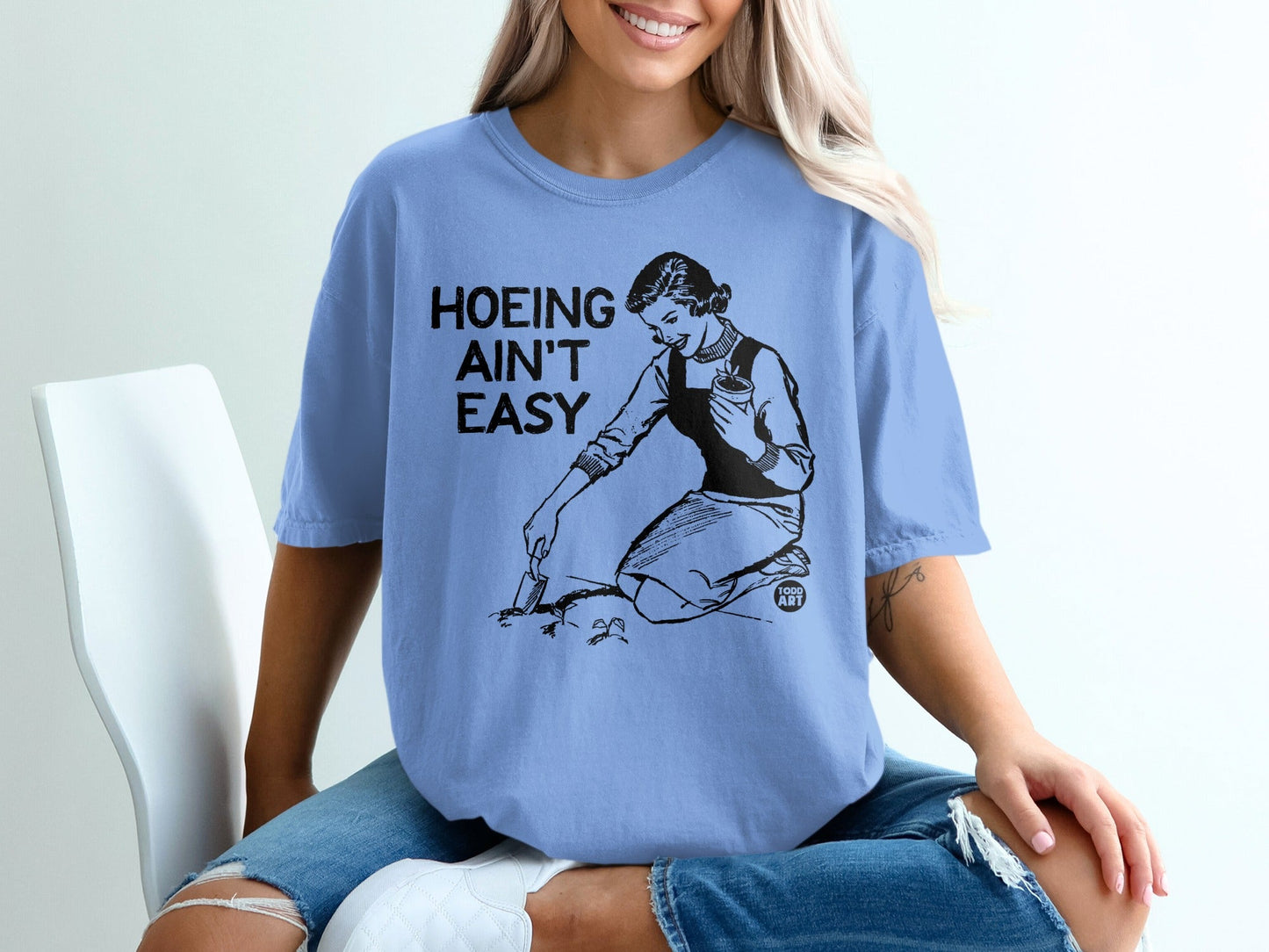 T-shirt with "Hoeing Ain't Easy" graphic of woman gardening.