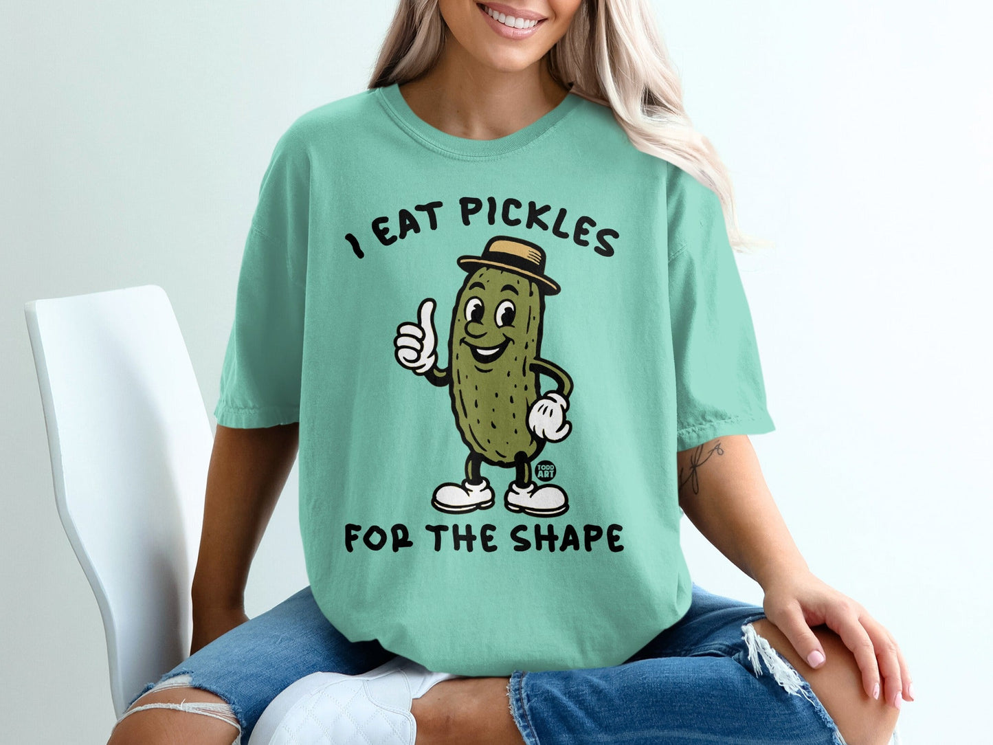 T-shirt with pickle character giving a thumbs up and text "I EAT PICKLES FOR THE SHAPE".