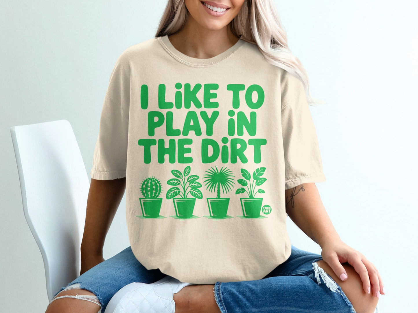 Cream t-shirt with green text "I LIKE TO PLAY IN THE DIRT" and potted plants.