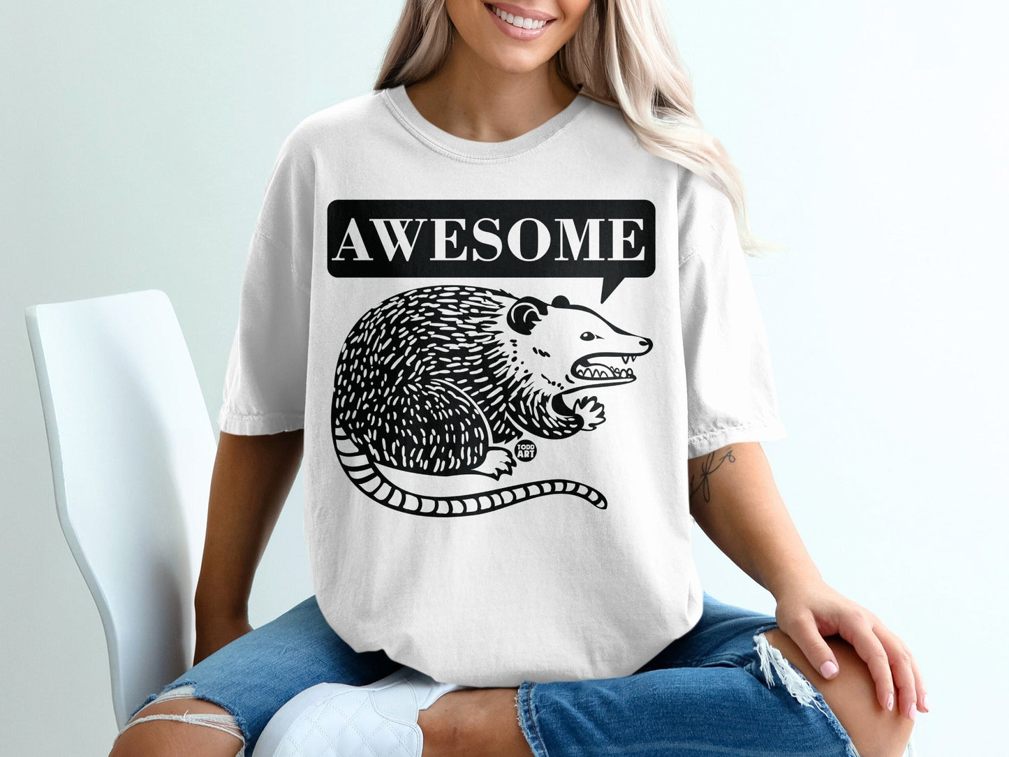 Black and white opossum graphic with "Awesome" in a speech bubble on a white t-shirt.