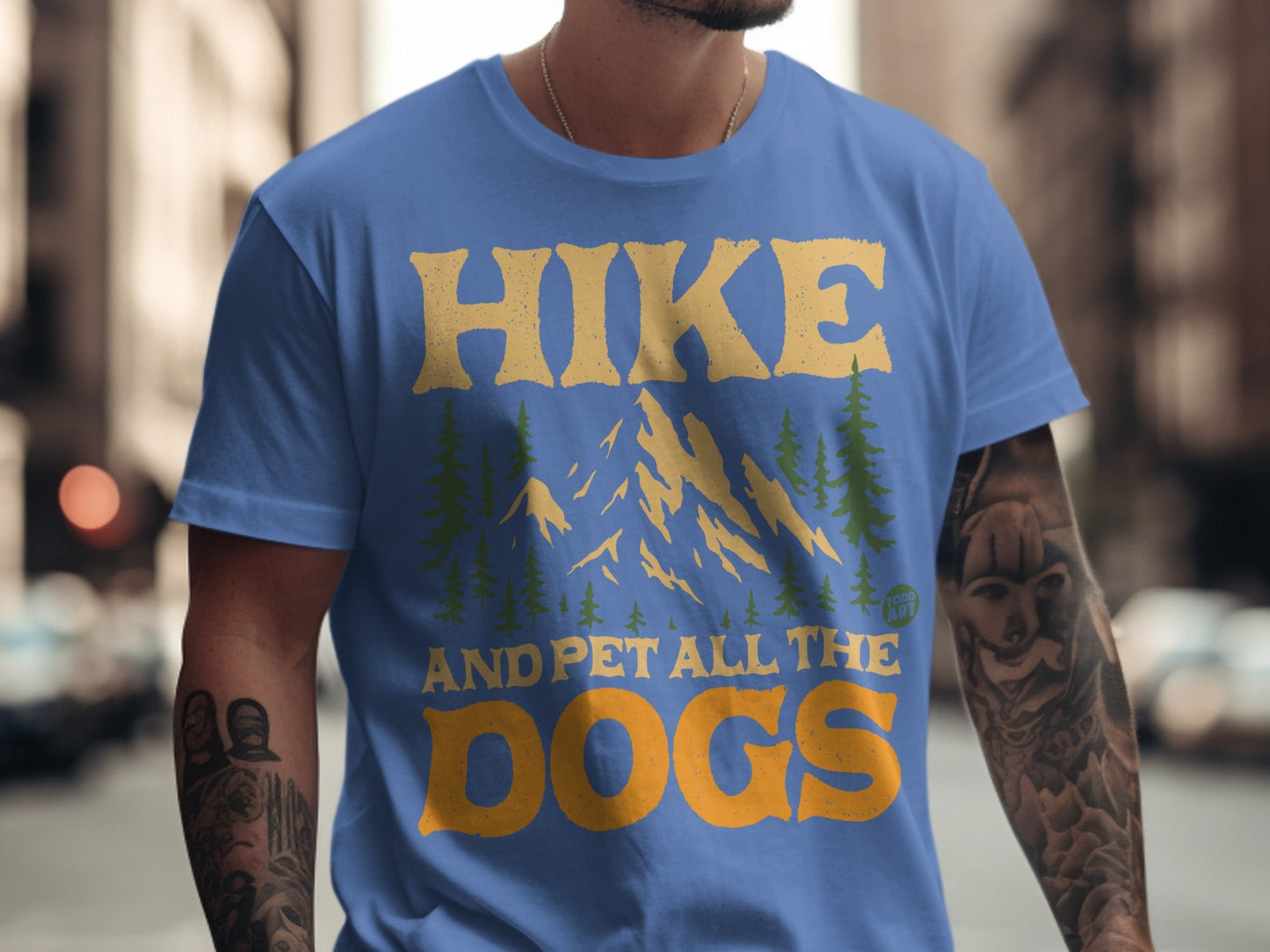Blue t-shirt with "Hike and pet all the dogs" text and mountain graphic.