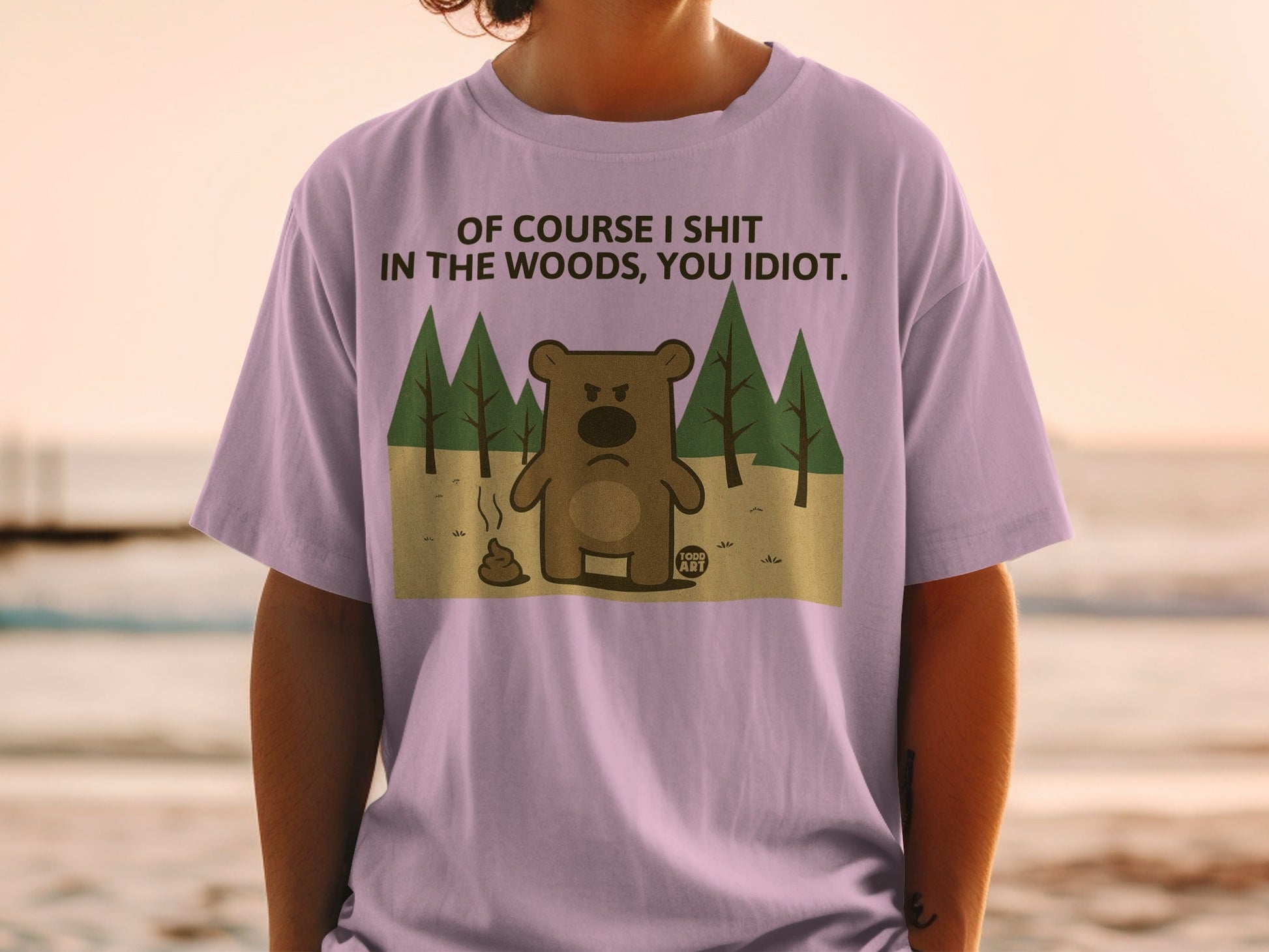 Purple t-shirt with a bear, woods, and text: "OF COURSE I SHIT IN THE WOODS, YOU IDIOT."