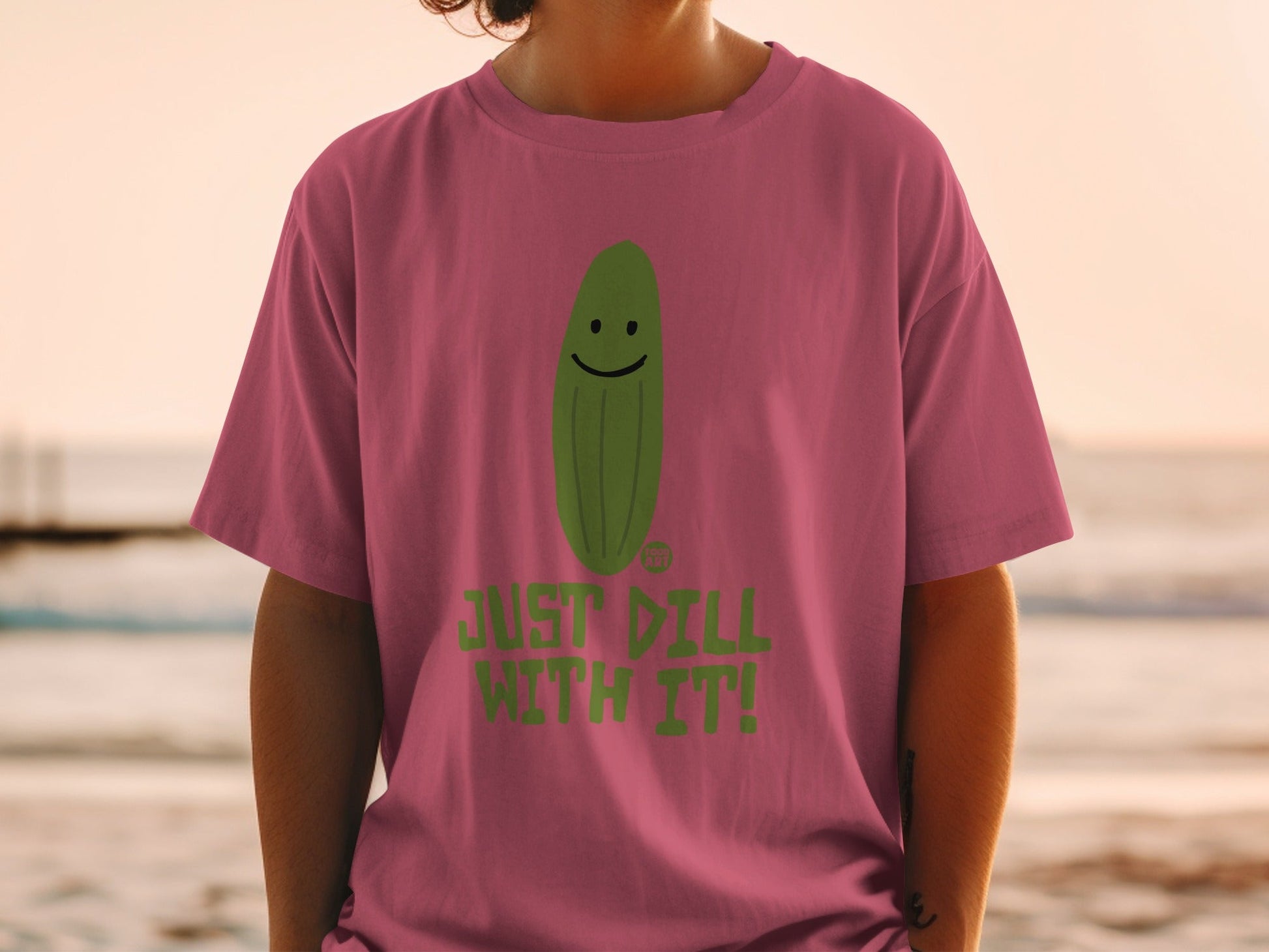 Pink t-shirt with a smiling pickle and the text "JUST DILL WITH IT!".