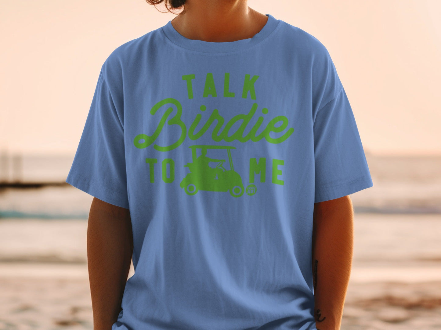 Light blue t-shirt with green text and golf cart graphic saying "Talk Birdie To Me".