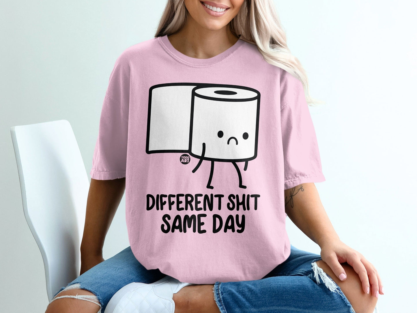 Pink t-shirt with cartoon toilet paper character and text "DIFFERENT SHIT SAME DAY".