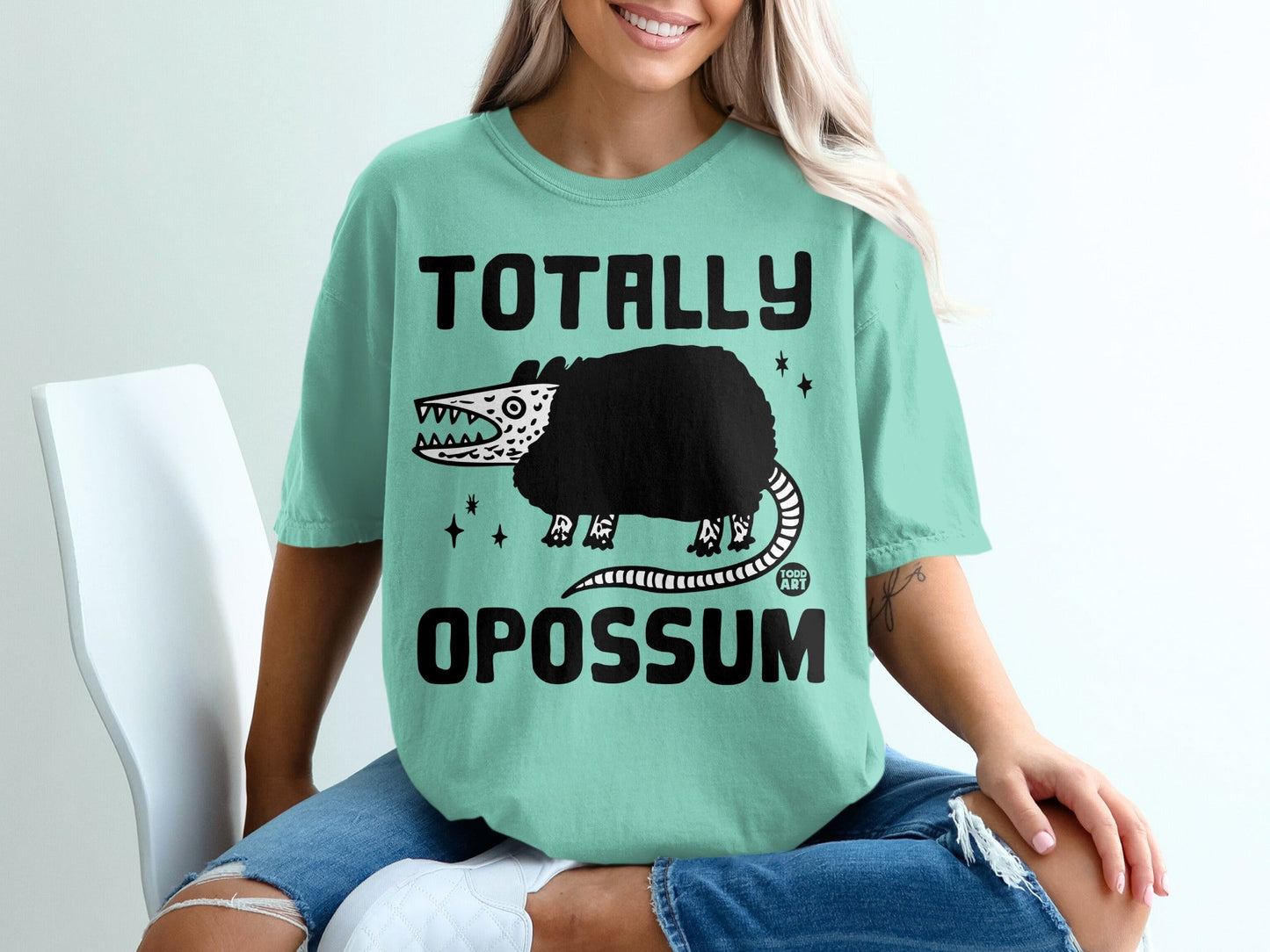 Light teal t-shirt with "Totally Opossum" text and a cartoon opossum graphic.