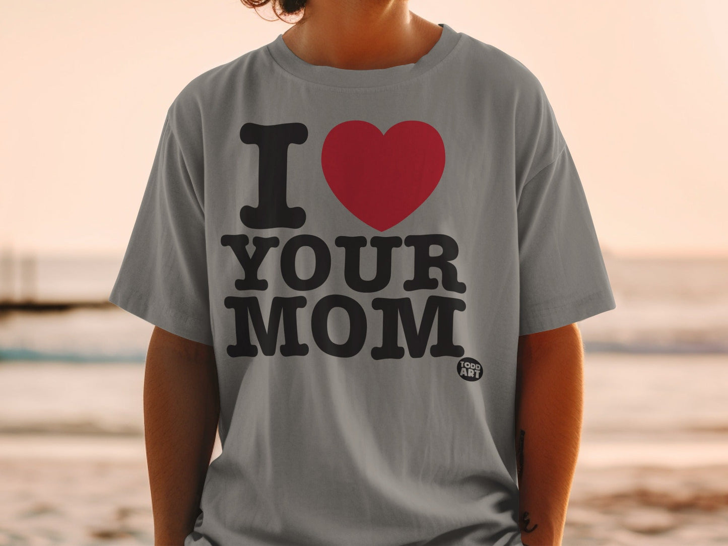 Grey t-shirt with black text "I ‚ù§Ô∏è YOUR MOM" and a small "GOOD ART" logo.