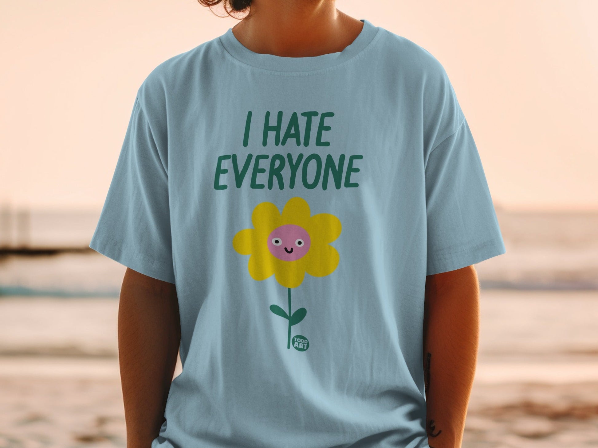 Light blue t-shirt with "I HATE EVERYONE" and a smiling flower graphic.
