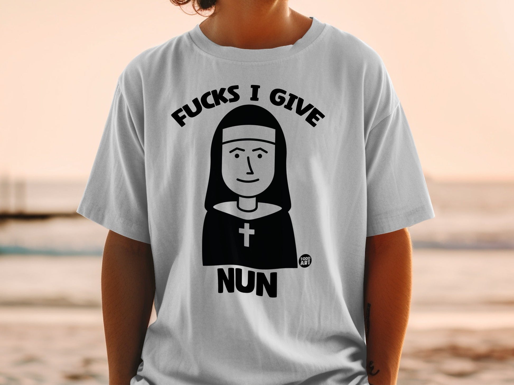 Black and white graphic on a white t-shirt: a nun illustration with "NUN" text.
