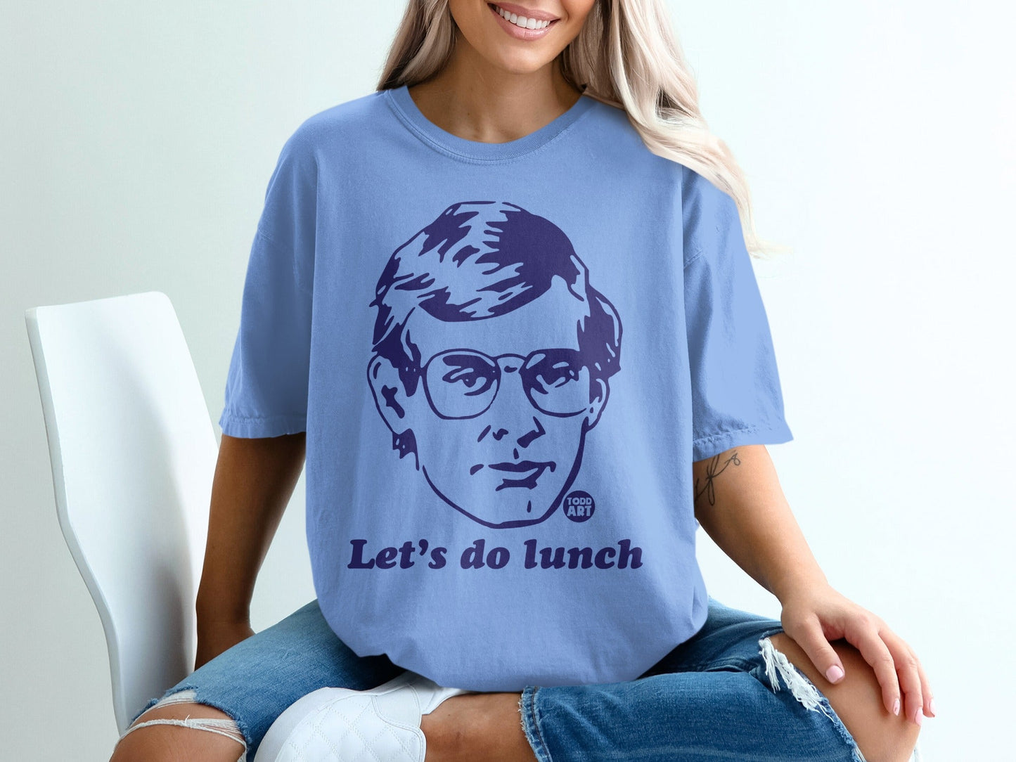 Light blue t-shirt with a dark blue graphic of a man's face and the text "Let's do lunch".