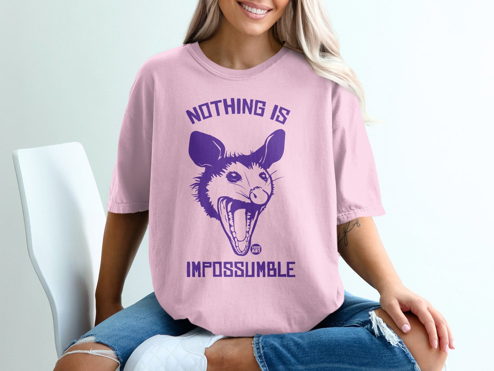 Pink t-shirt with purple possum graphic and text "NOTHING IS IMPOSSUMBLE".
