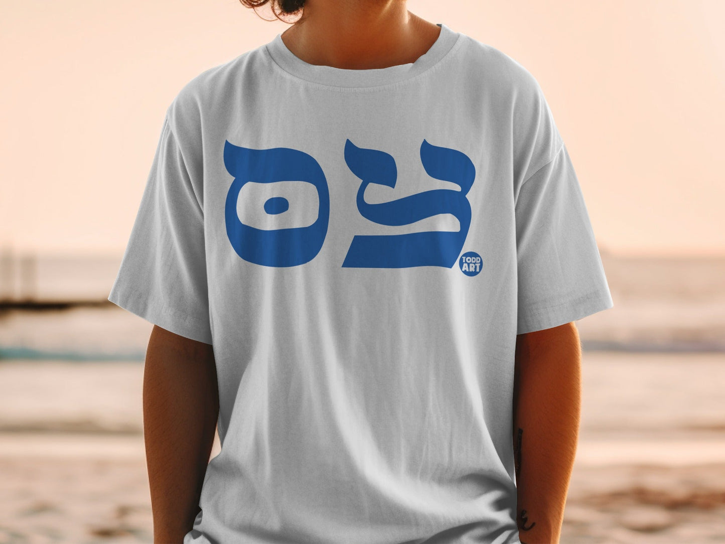 White t-shirt with blue Hebrew text and TODD ART logo on the chest.