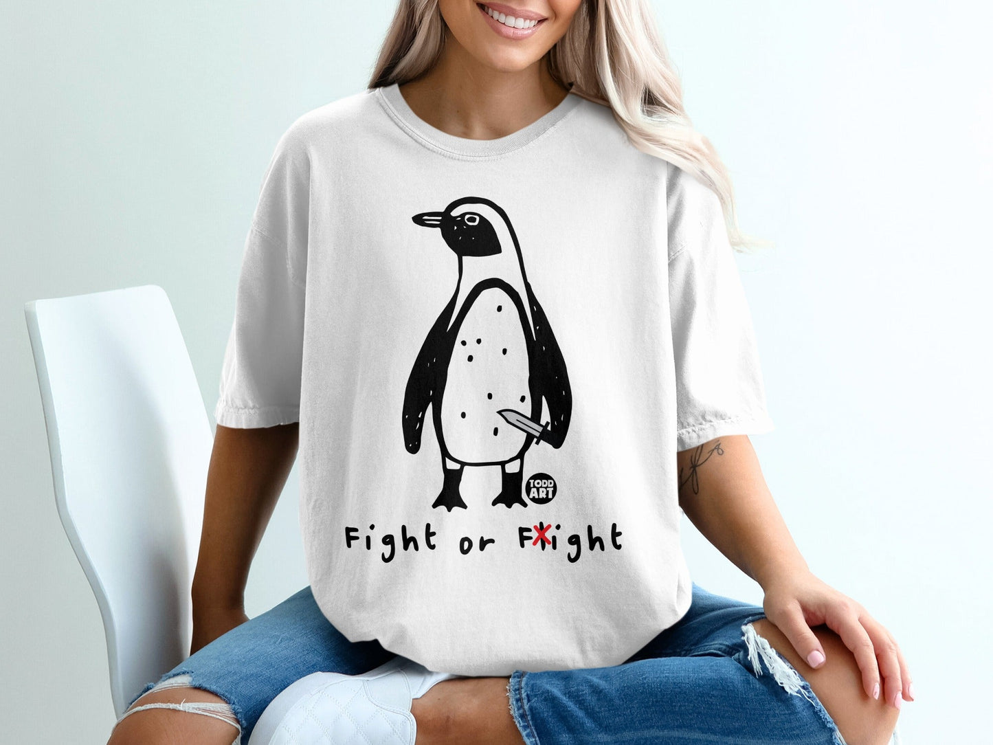 White t-shirt with a penguin drawing holding a knife and text "Fight or Flight".