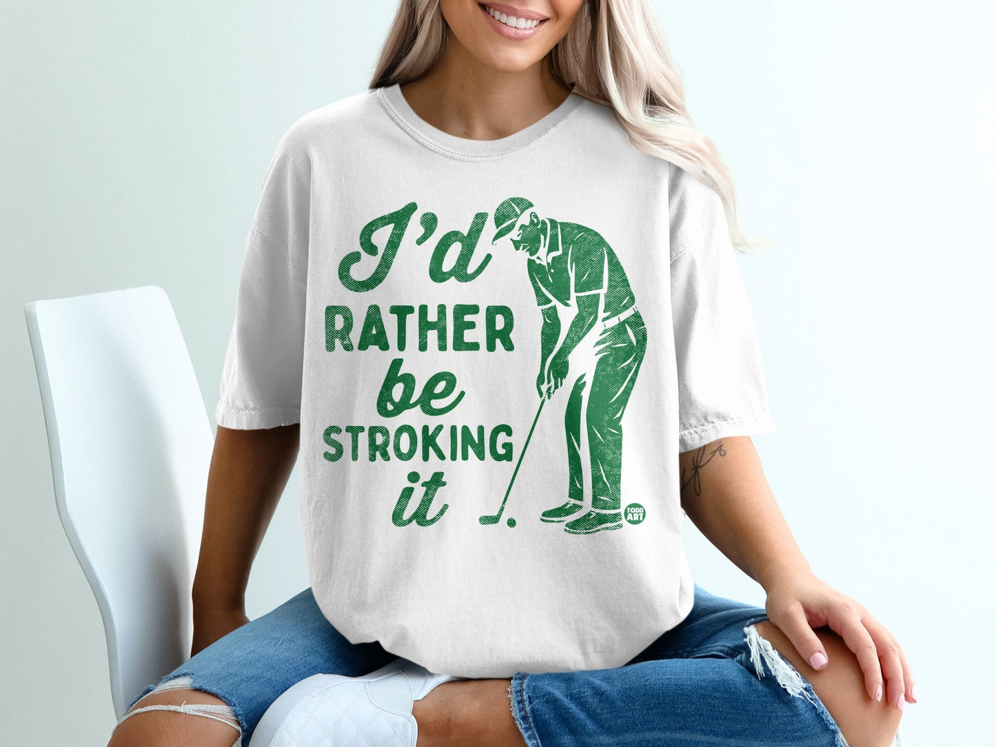 White t-shirt with green graphic of golfer and text "I'd rather be stroking it".