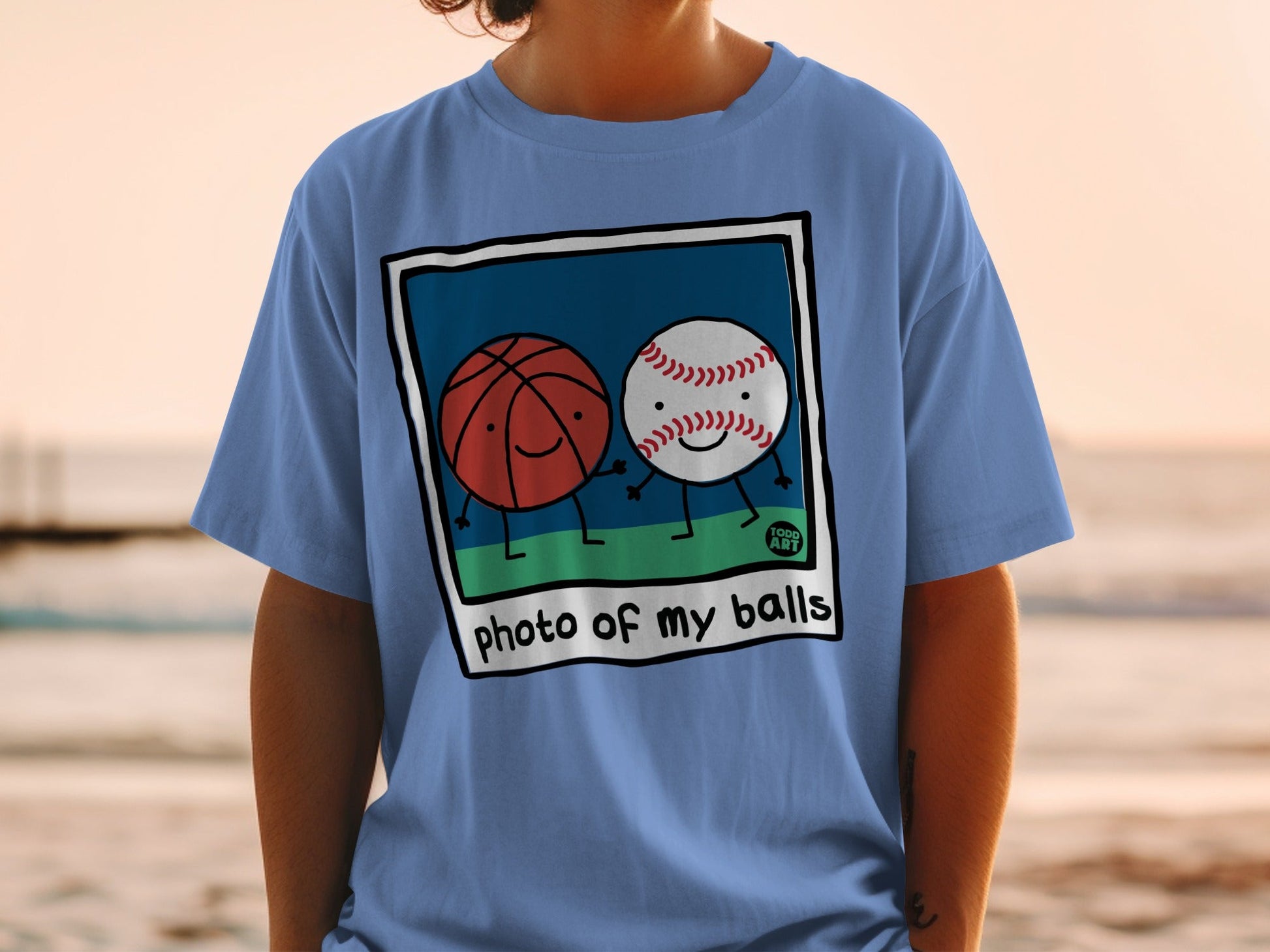 T-shirt with cartoon basketball and baseball on a green field, text reads "photo of my balls".