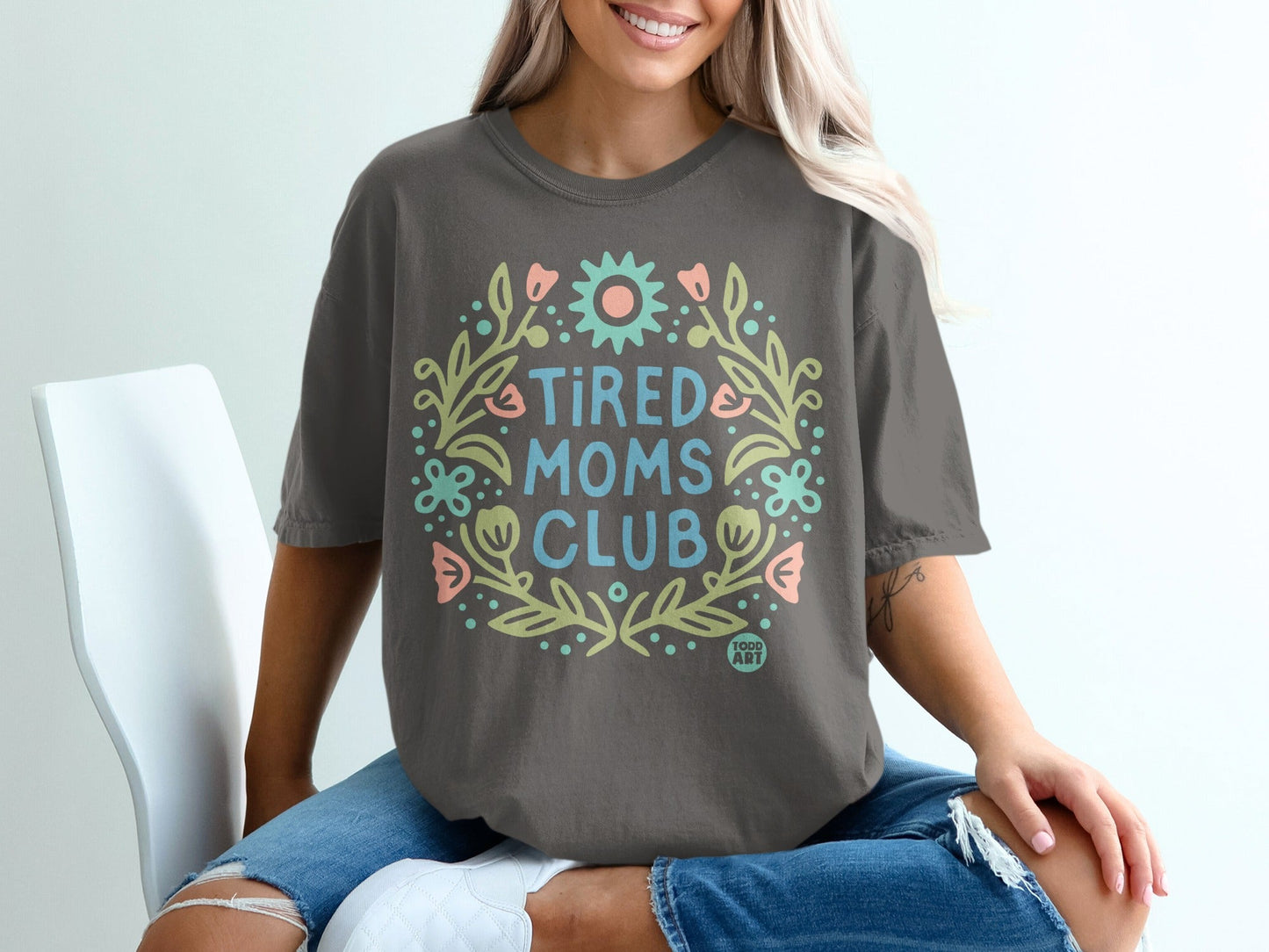 Tired Moms Club graphic tee with floral wreath and pastel accents.