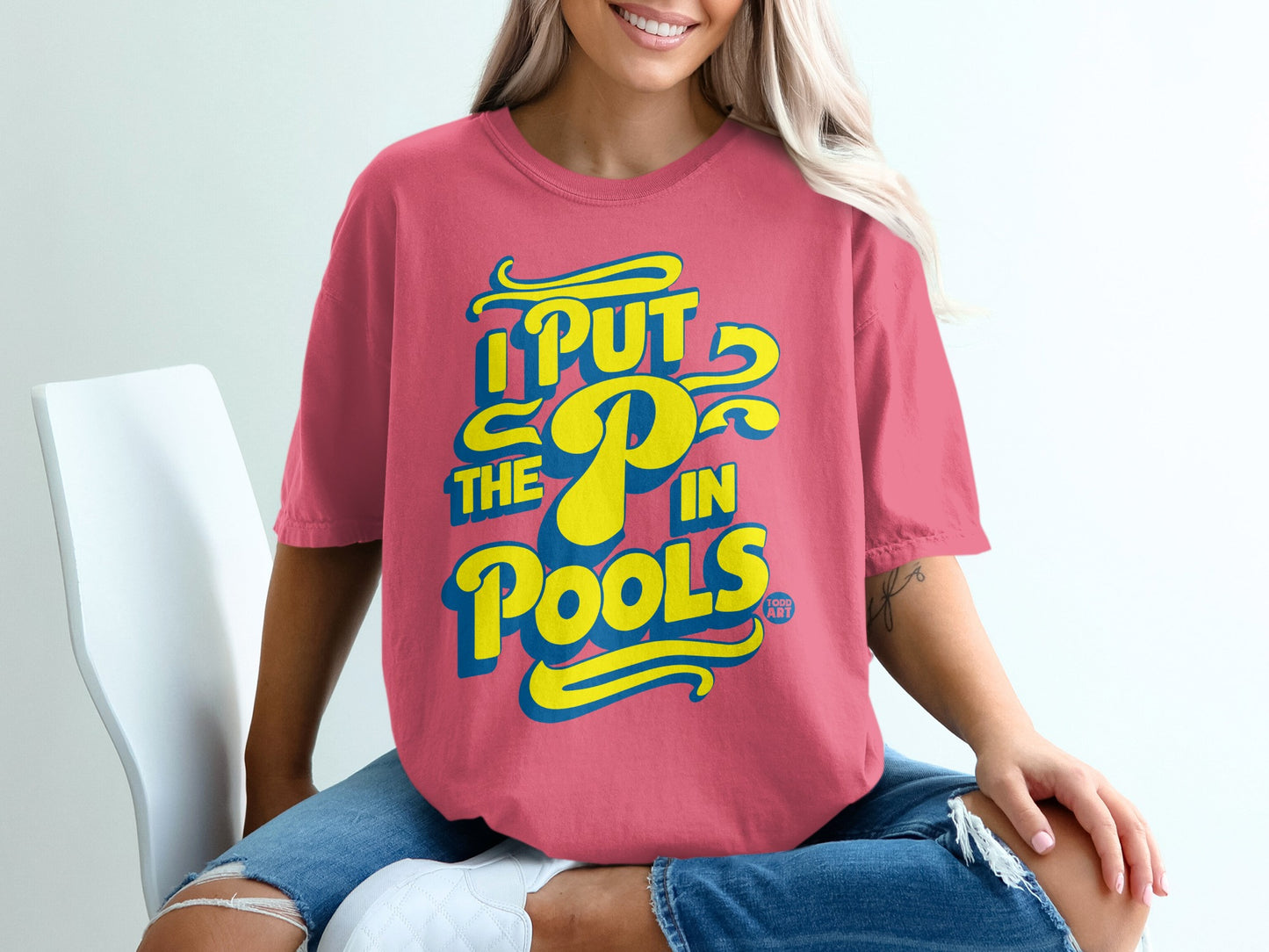 Coral t-shirt with yellow and blue text reading "I PUT THE P IN POOLS".