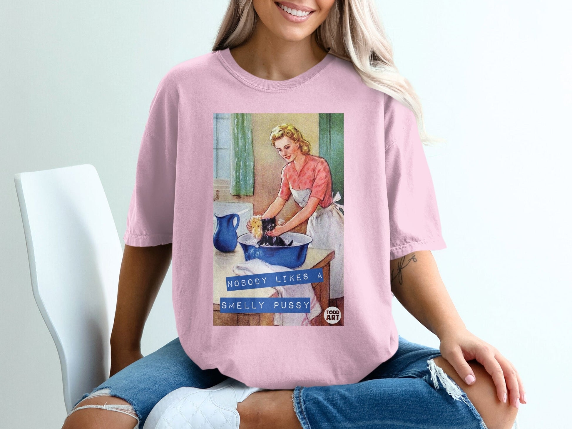 Woman in pink shirt with retro graphic of a woman washing a black cat in a sink.