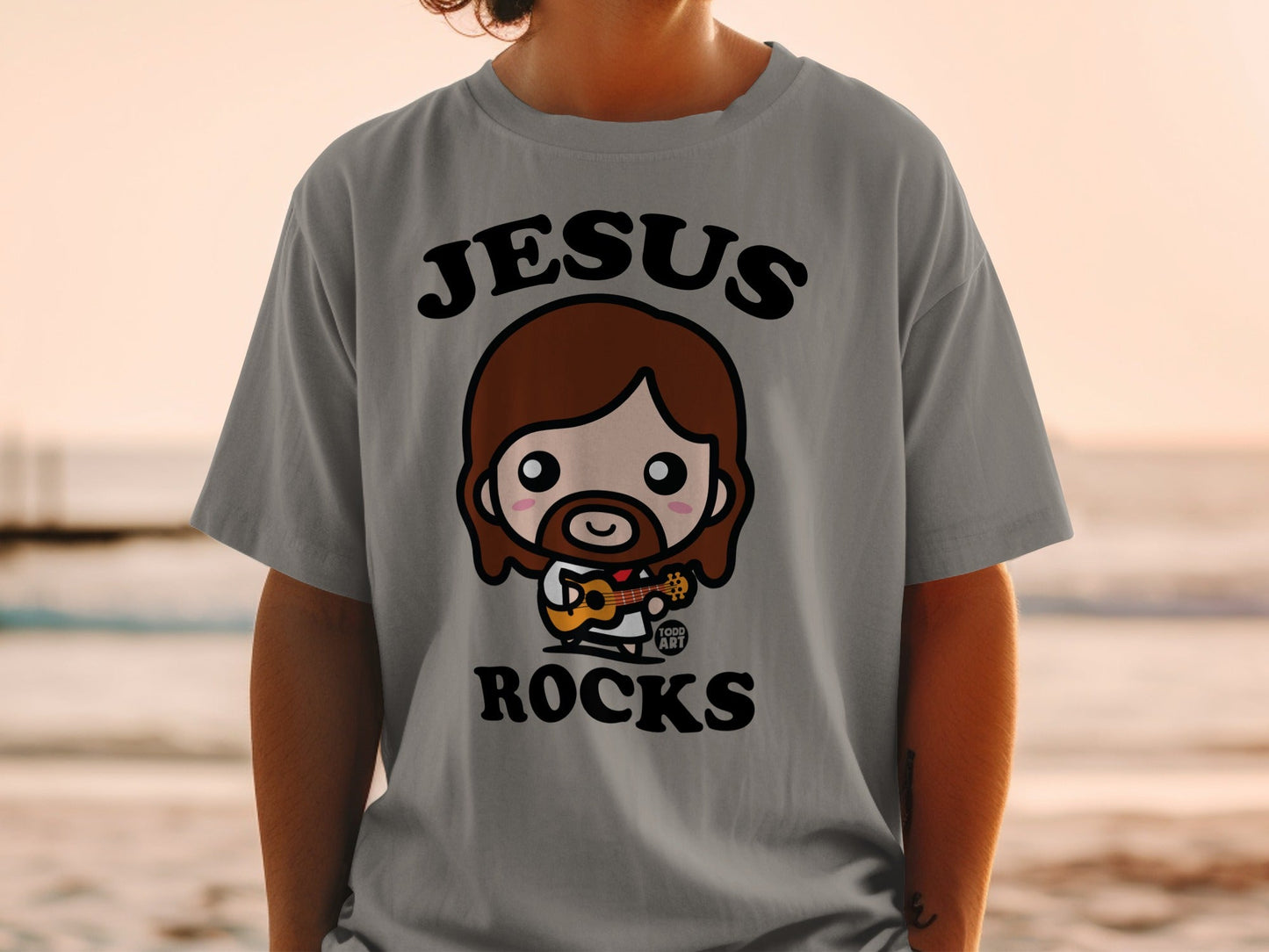 Chibi Jesus with guitar on gray t-shirt, "Jesus Rocks" text.