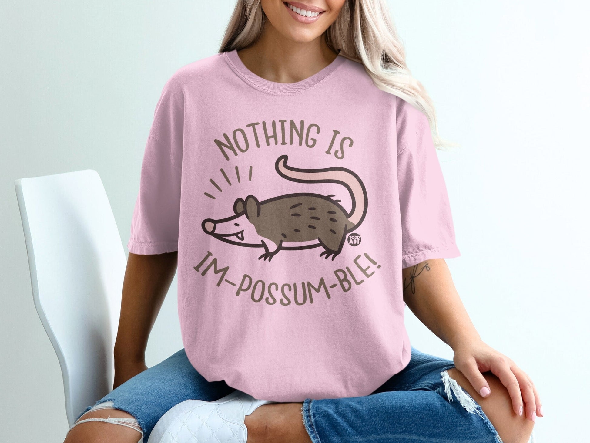Pink t-shirt with a cartoon possum and text "NOTHING IS IM-POSSUM-BLE!".