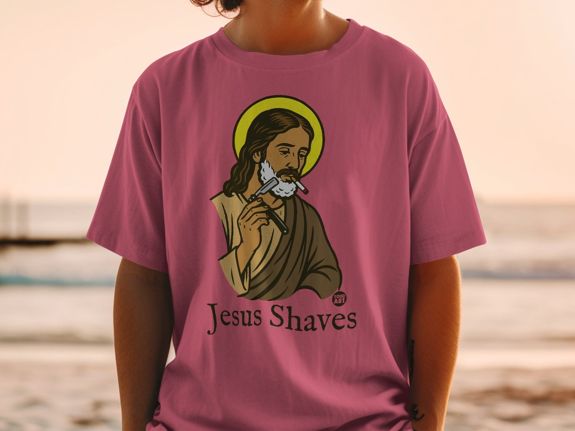 Jesus with halo shaves with a razor, text "Jesus Shaves" on t-shirt.