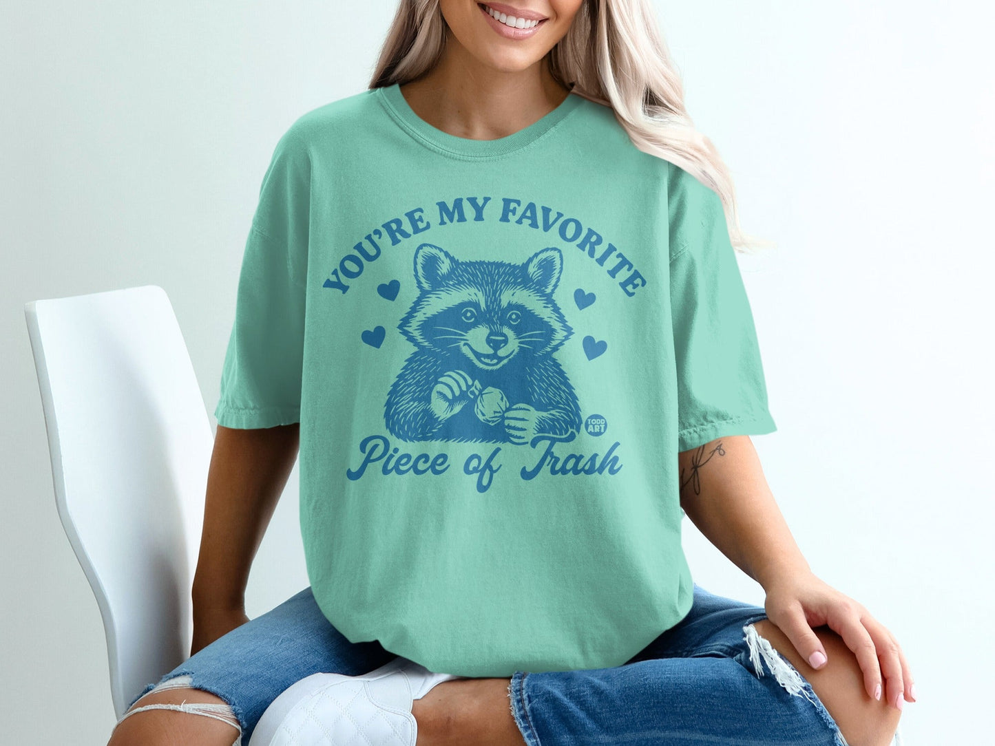 Mint t-shirt with raccoon graphic and "You're my favorite piece of trash" text.