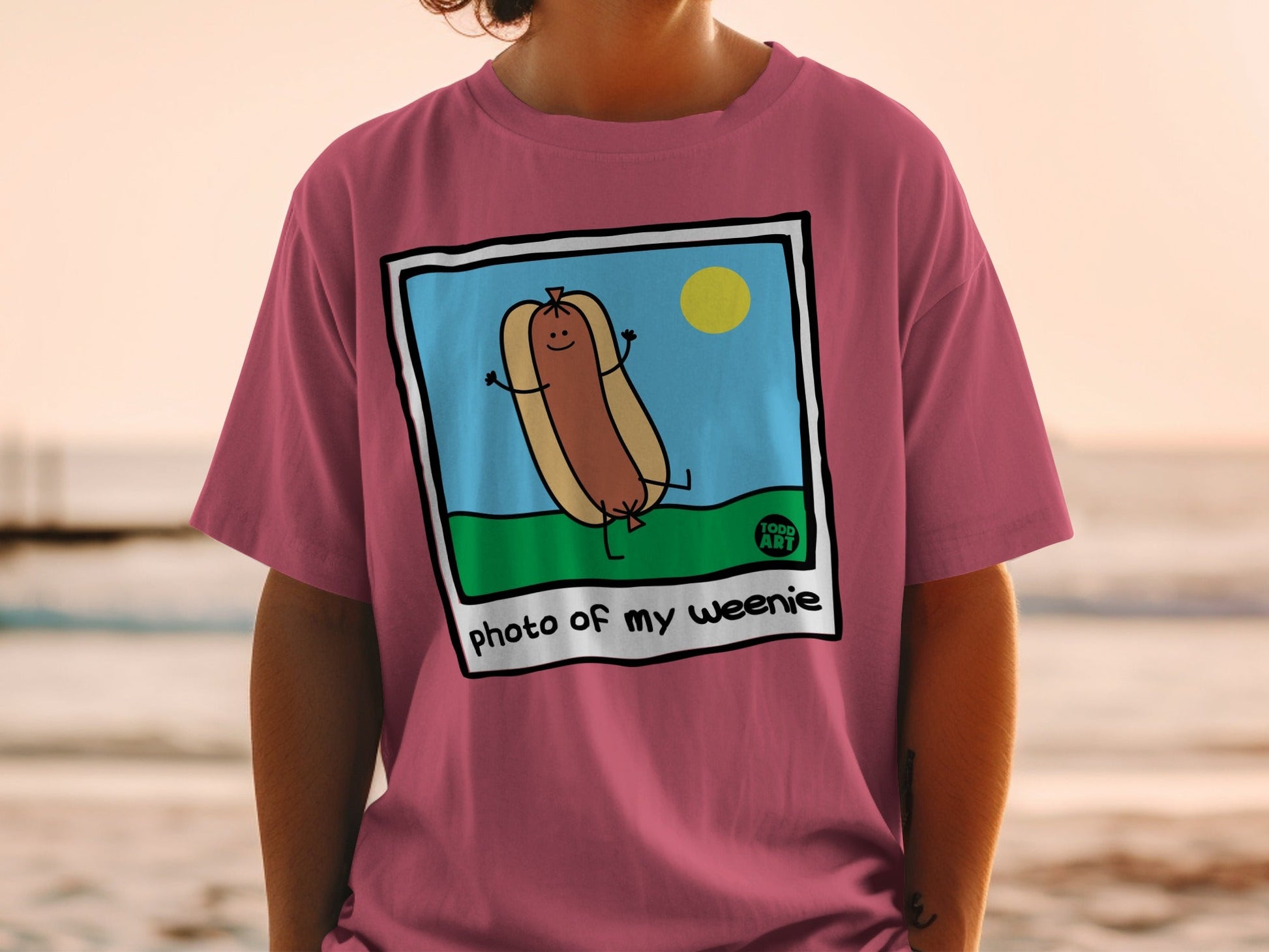 Cartoon hot dog with arms raised on grass, "photo of my weenie" text.