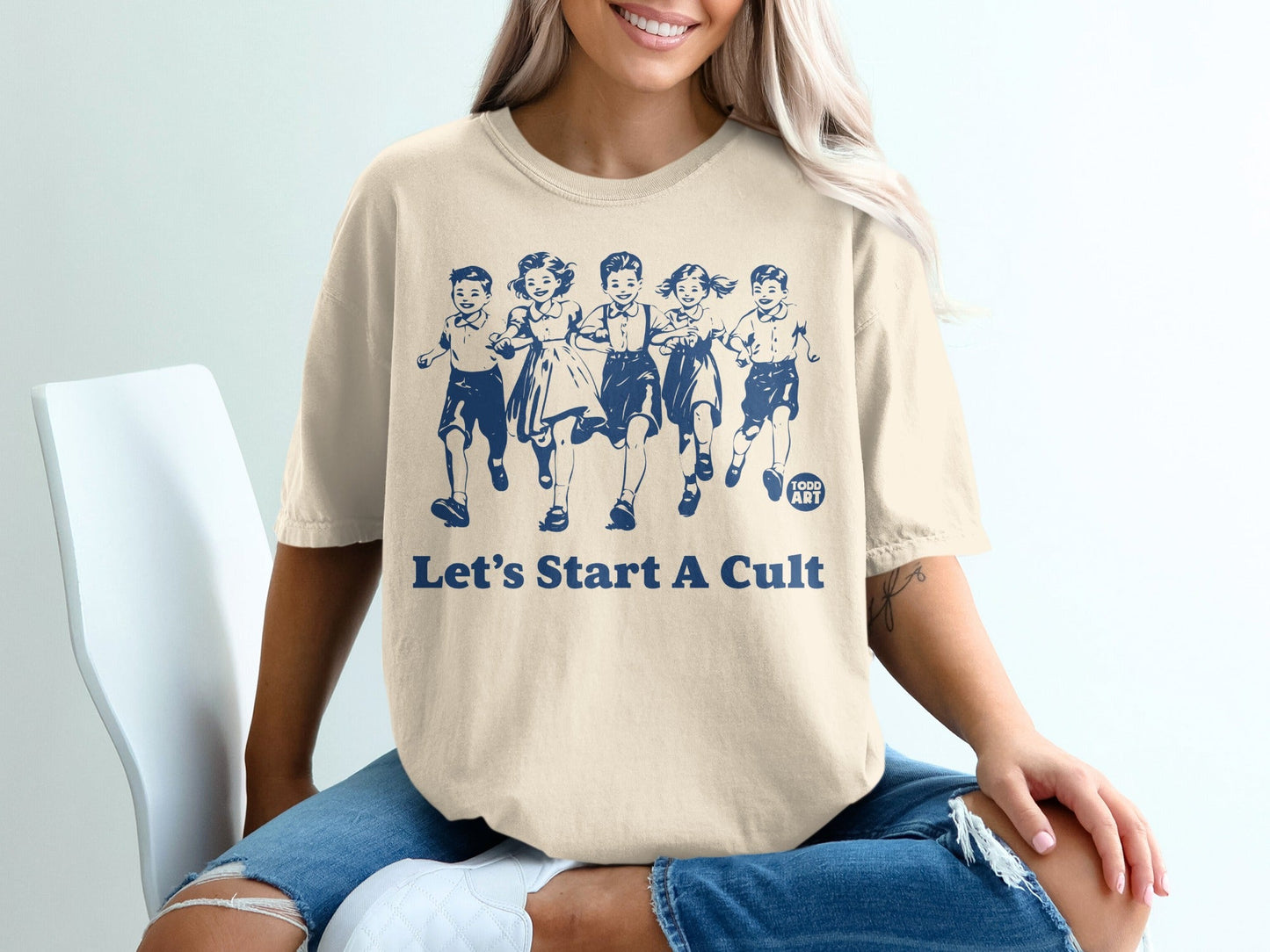 T-shirt with navy blue graphic of children running and text "LET'S START A CULT".