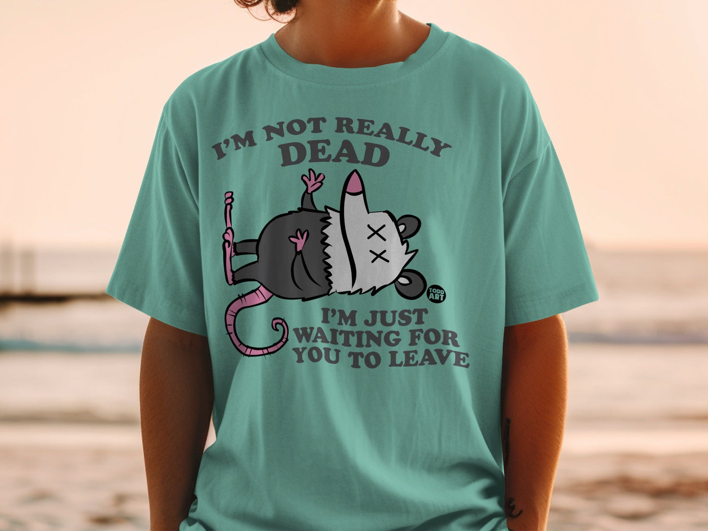 T-shirt with cartoon opossum playing dead and text "I'm not really dead I'm just waiting for you to leave."