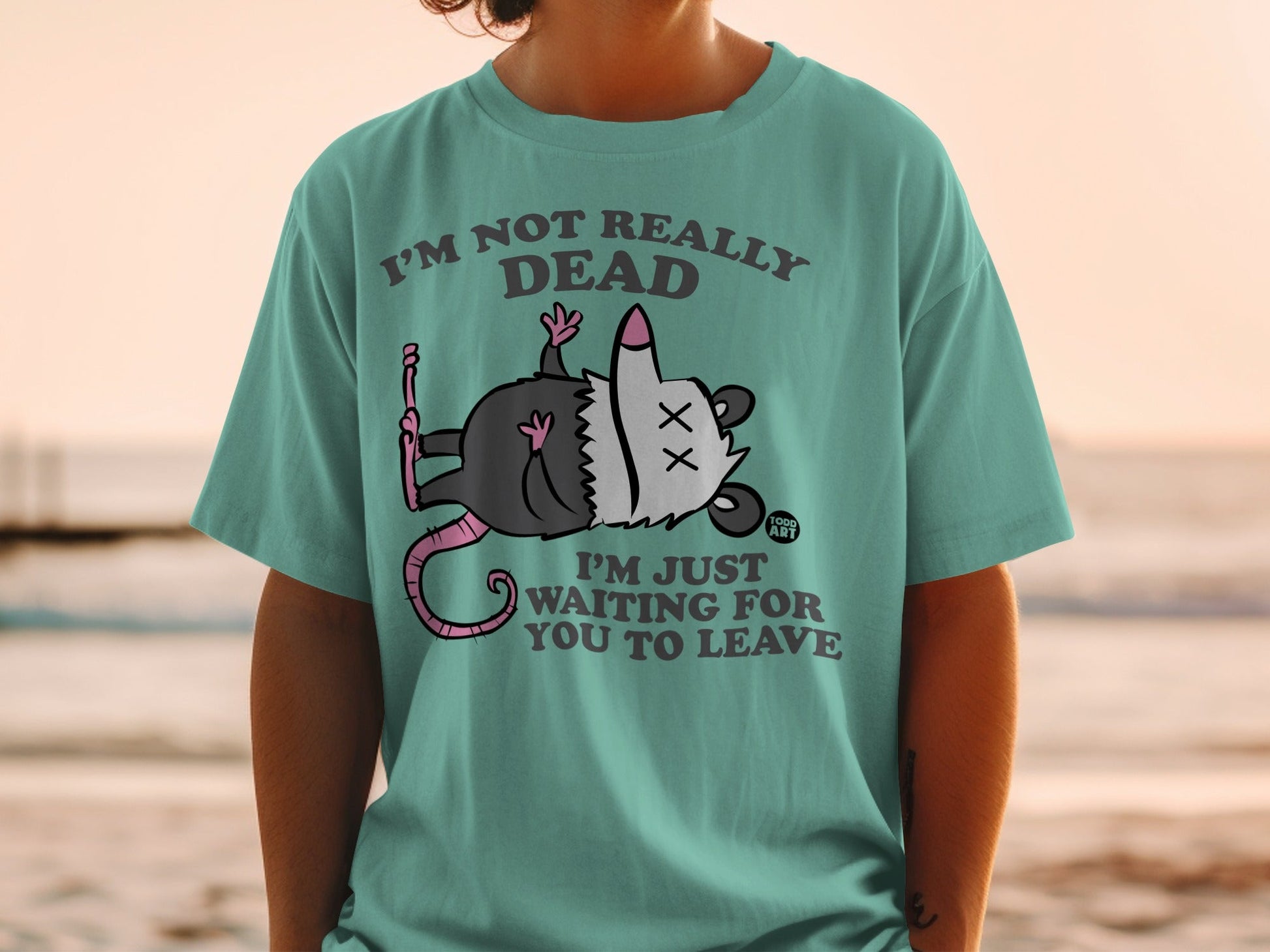 T-shirt with cartoon opossum playing dead and text "I'm not really dead I'm just waiting for you to leave."