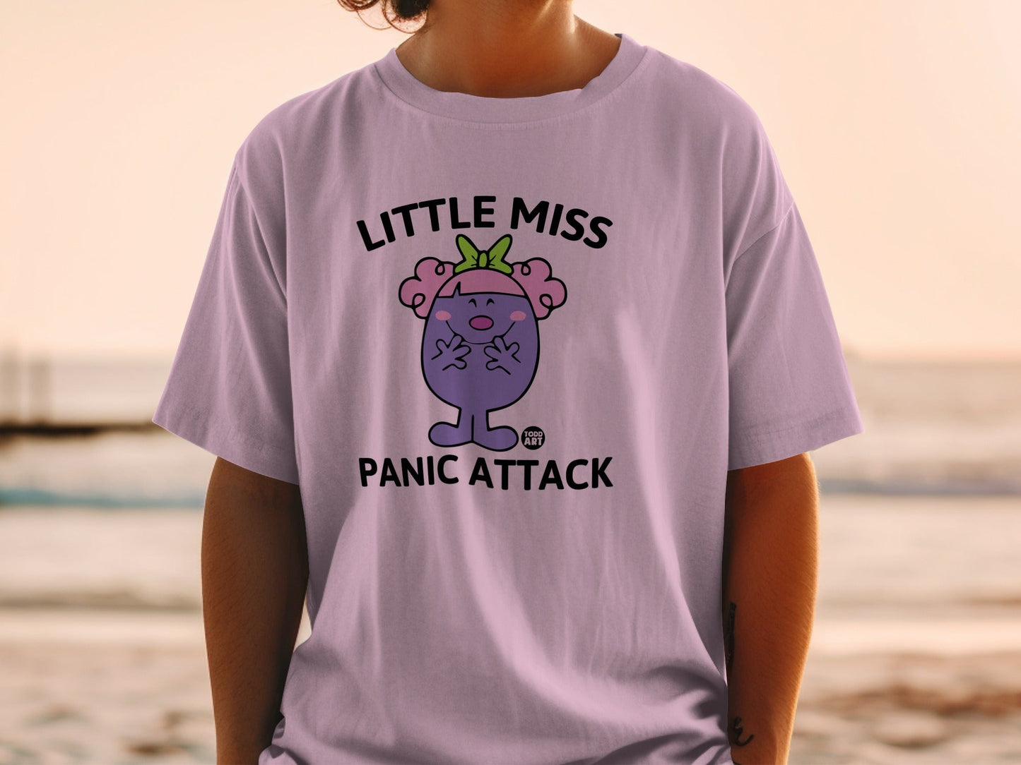 Little Miss Panic Attack graphic t-shirt with purple character and green bow.
