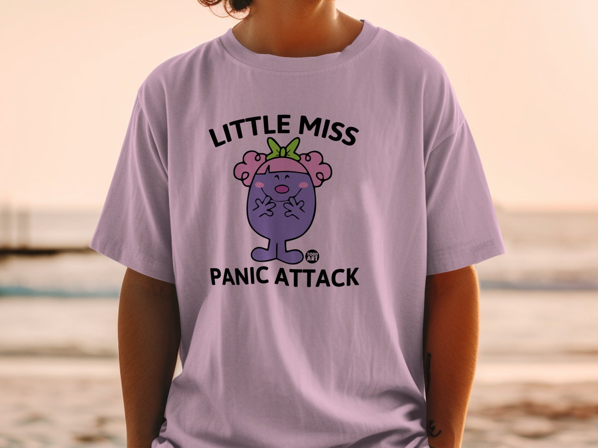 Little Miss Panic Attack graphic t-shirt with purple character and green bow.
