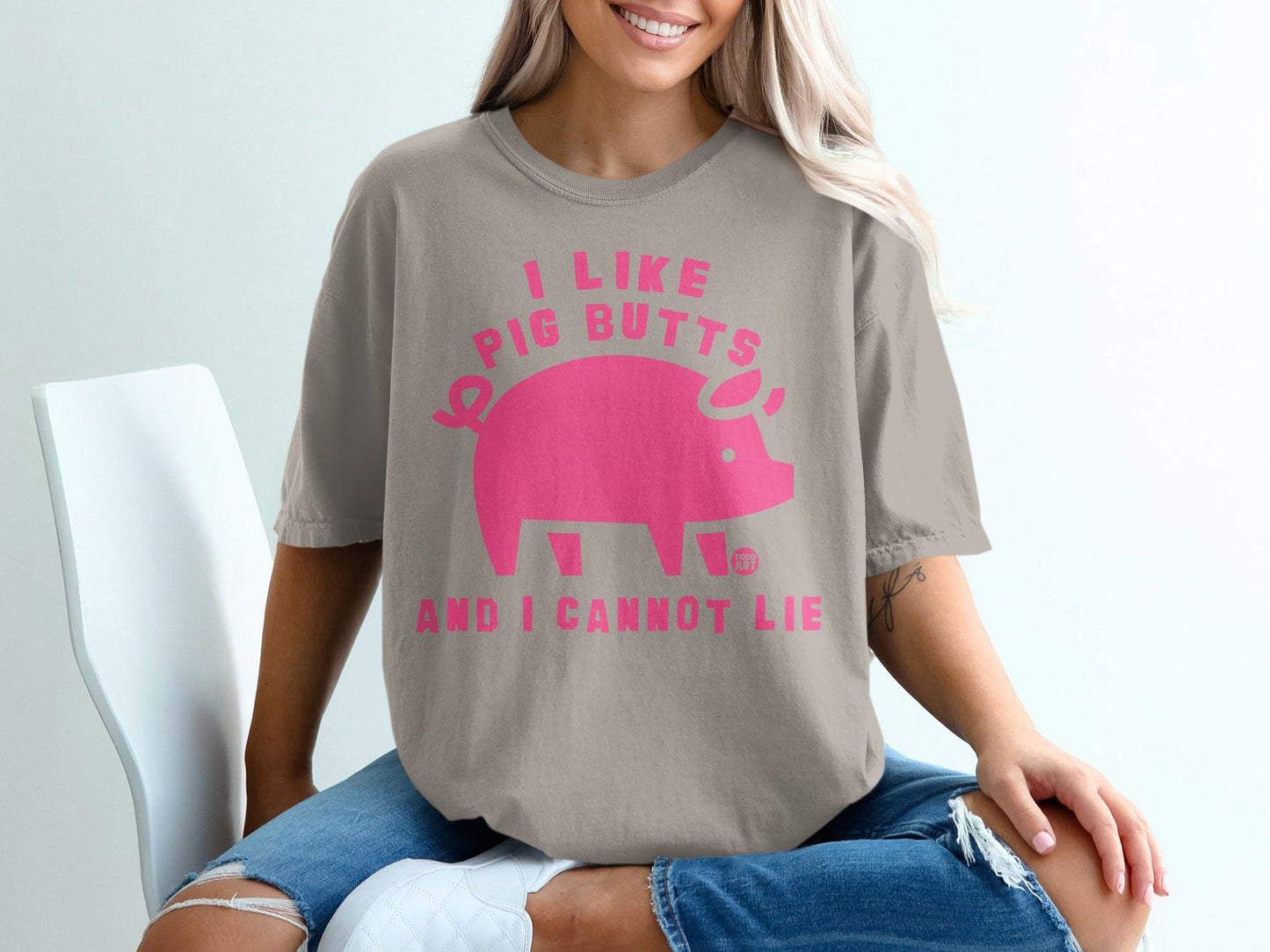 "I like pig butts and I cannot lie" text on a taupe t-shirt with a pink pig graphic.
