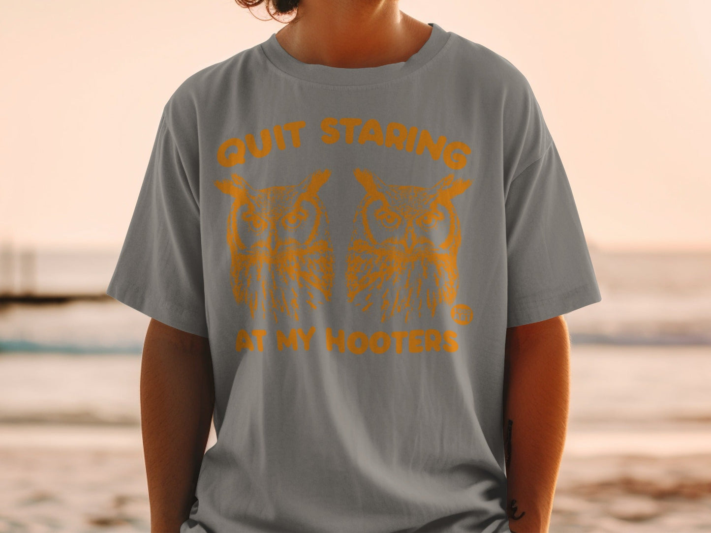 Grey t-shirt with orange graphic of two owls and text "Quit Staring At My Hooters".
