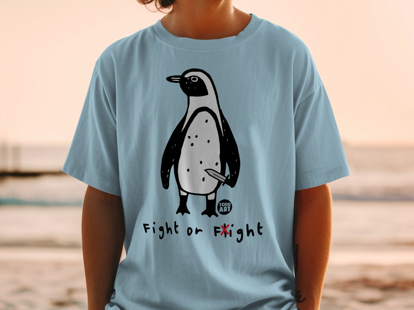 Light blue t-shirt with a cartoon penguin holding a knife, text "FIGHT OR FLIGHT".