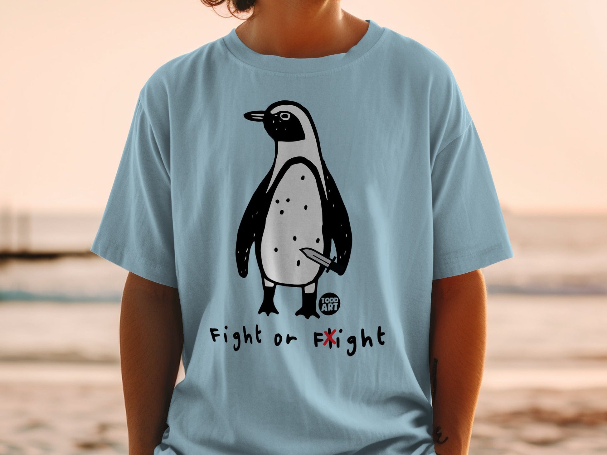 Light blue t-shirt with a cartoon penguin holding a knife, text "FIGHT OR FLIGHT".